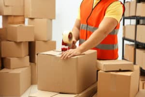 Operaio con gilet ad alta visibilità che prepara scatole di cartone