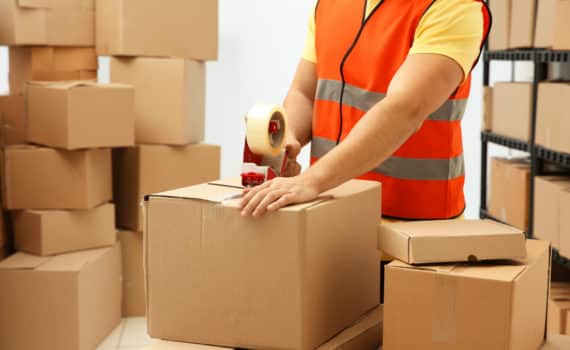 Operaio con gilet ad alta visibilità che prepara scatole di cartone