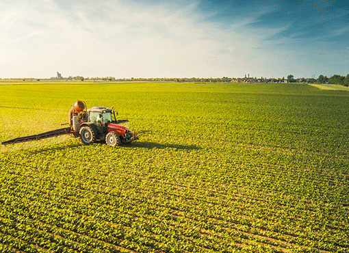 Campo coltivato con un trattore in lontananza