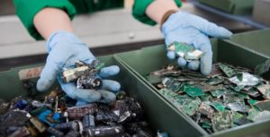 Mani con i guanti smistano componenti elettronici su un nastro
